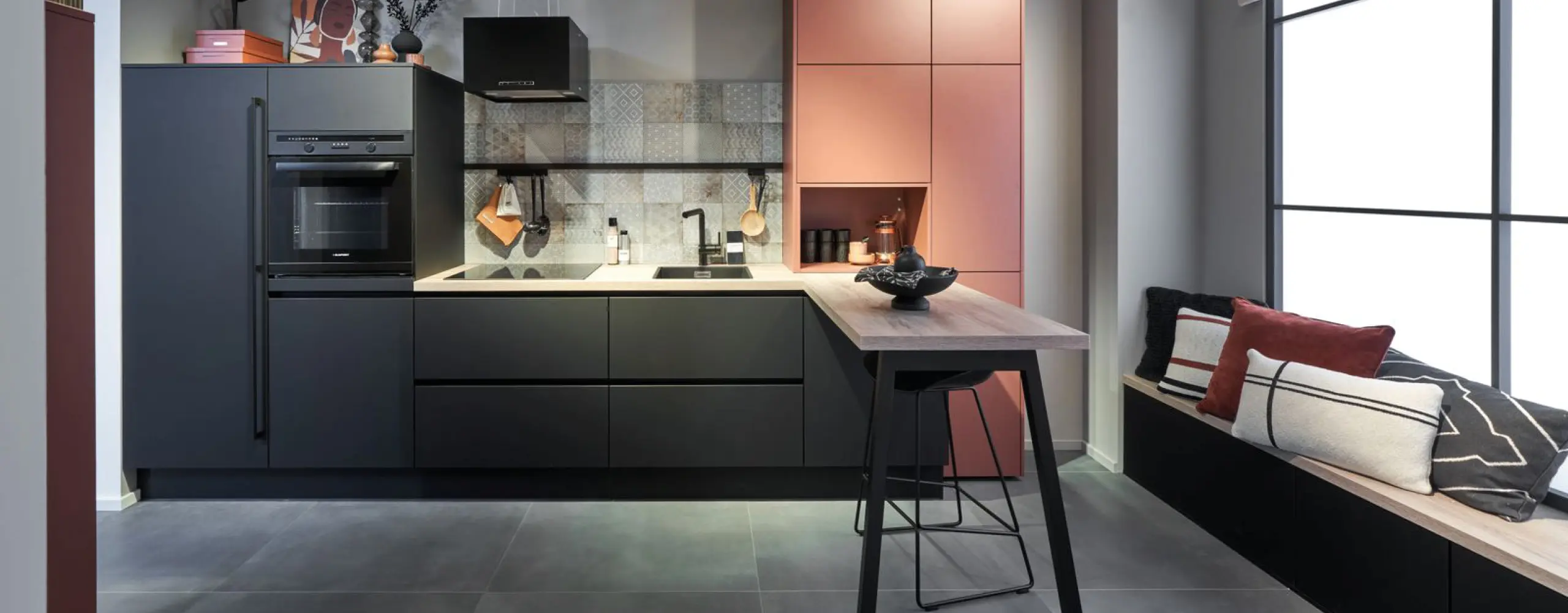 Moderne Küche in Schwarz und Rosé mit Holzarbeitsplatte, offenen Regalen und stilvoller Sitzbank. Designorientiertes Küchendesign mit Fliesenrückwand und eleganter Lichtstimmung.